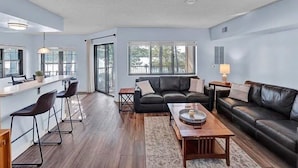 A modern living room with a black leather sofa, a wooden coffee table, and a bar area with stools. - Big Boulder Relaxation, Slopes Up, Big Boulder, Jack Frost Ski Resorts  (Lake Harmony)