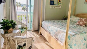 Un dormitorio con cama, una silla, una mesa, un ventilador de techo y vistas al exterior.