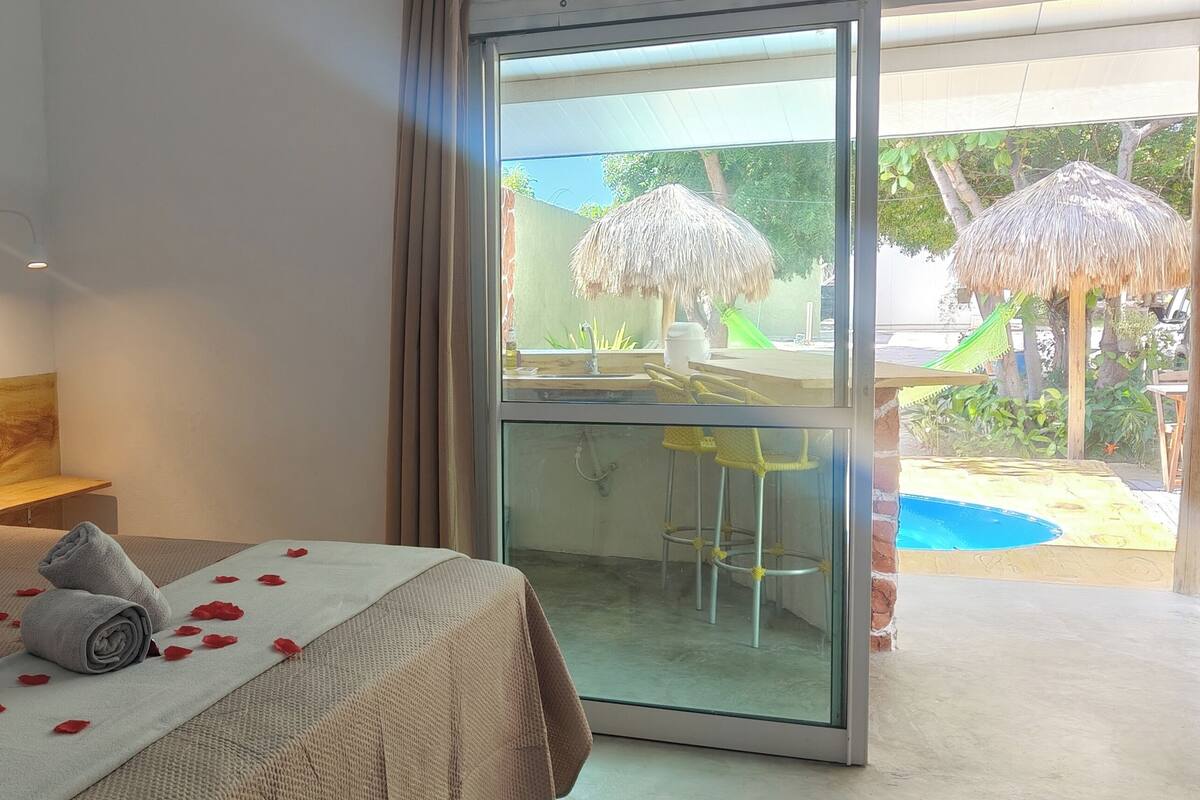 A bedroom with a bed, pillows, a towel, and rose petals.