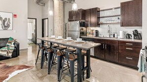 A modern kitchen with dark wood cabinets, a stainless steel refrigerator, and a dining area with bar stools.