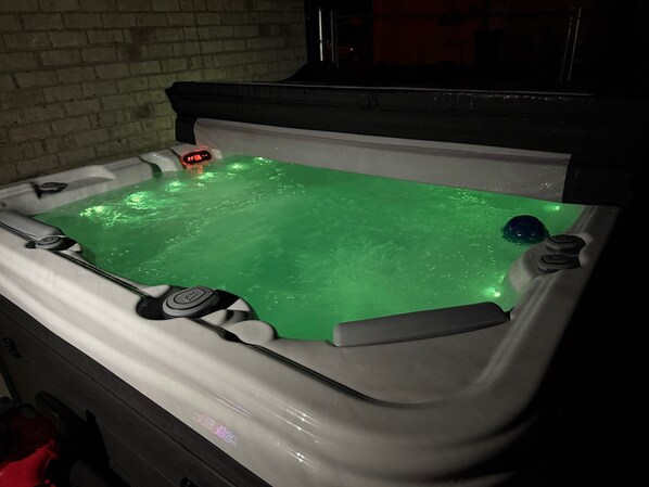 A hot tub with a digital control panel and a green water feature.