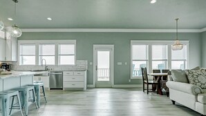 A spacious kitchen with a dining area, a white sofa, and a view of the outdoors. - The Lazy Turtle, Beachfront (Crystal Beach)