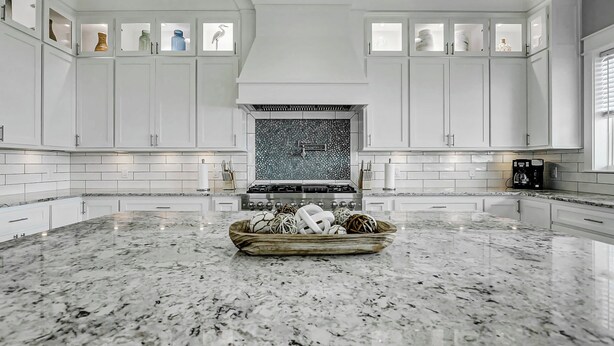 A kitchen with white cabinets, a granite countertop, and a decorative bowl in the center. - The Lazy Turtle, Beachfront (Crystal Beach)