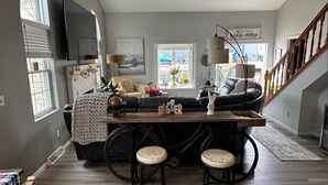 Ein modernes Wohnzimmer mit einer Couch, einem Couchtisch und einem Fernseher. Eine Treppe führt zu einer weiteren Ebene.