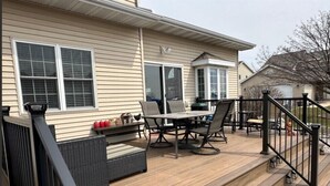 Eine Terrasse mit Tisch und Stühlen, einer kleinen Sitzecke und einem Geländer.