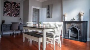 A dining area with a table and chairs, a fireplace, and artwork on the walls.