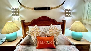 Una cama con cabecera de madera, dos lámparas de noche y un gran cuerno decorativo sobre la cama.