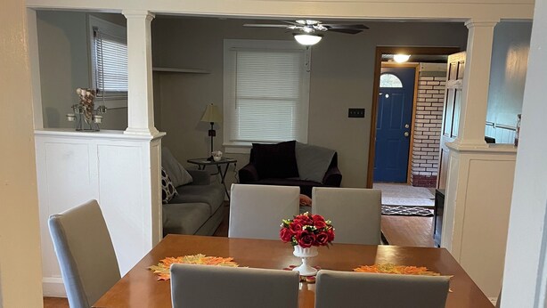 A dining area with a wooden table, four grey chairs, and a ceiling fan with a light fixture. - Charming 2-bedroom house in busy downtown Indianapolis with WiFi, AC. (Indianapolis)