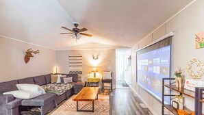 A modern living room with a sectional sofa, a wooden coffee table, and a ceiling fan. - Beaver Lodge - 33 Acres of Secret Getaway, House with AC, RV Parking (Wetaskiwin)