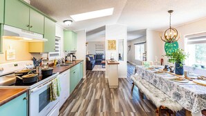 A spacious kitchen with a dining area, featuring a long wooden table and a chandelier. - Beaver Lodge - 33 Acres of Secret Getaway, House with AC, RV Parking (Wetaskiwin)