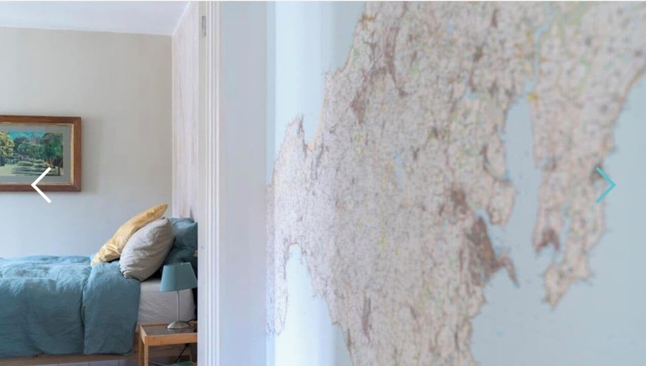 Un dormitorio con una cama, una mesita de noche, una lámpara y un mapa en la pared.