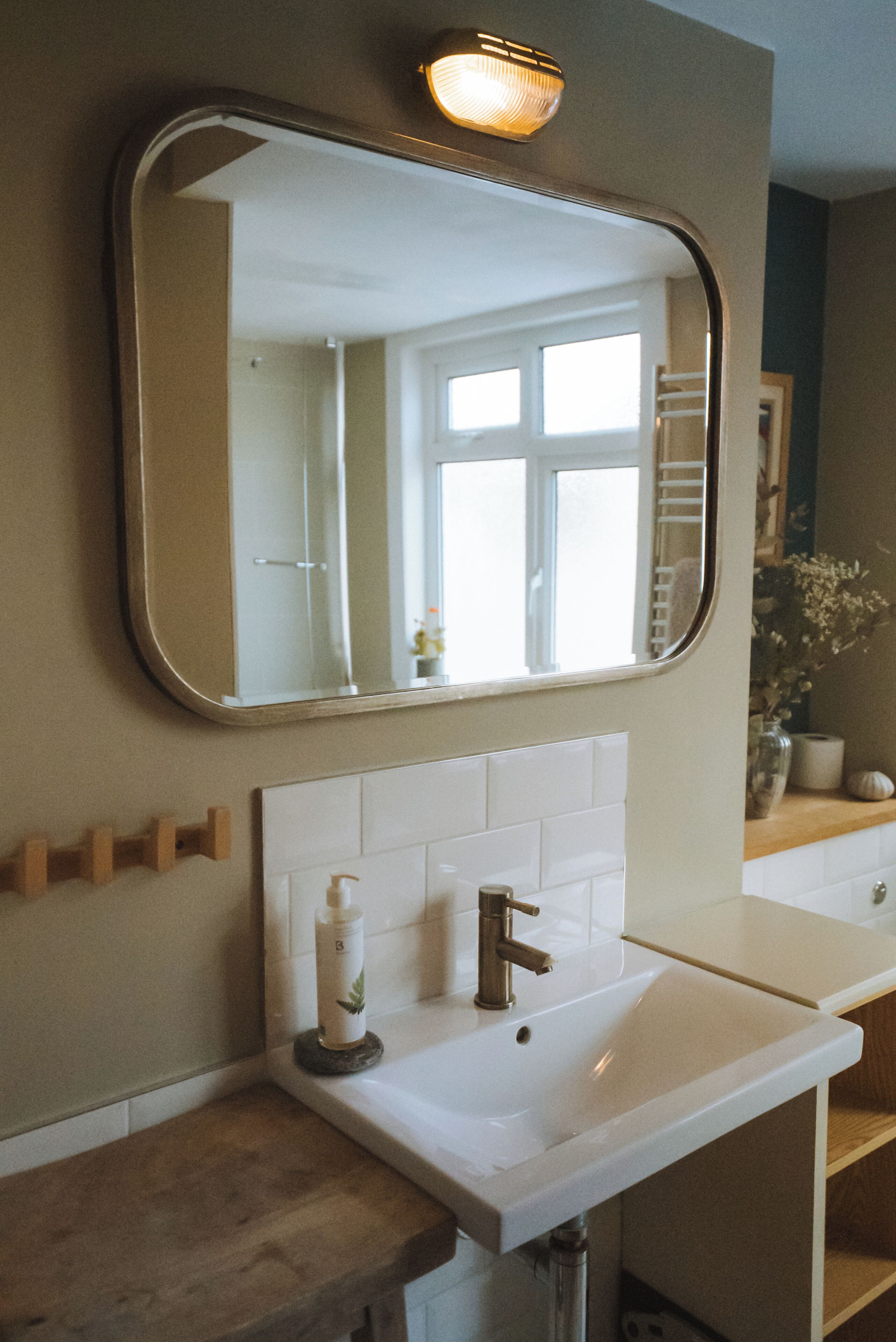 A bathroom with a large mirror, white sink, and a towel rack.
