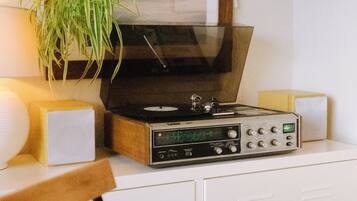 Una habitación con un armario de madera, un tocadiscos, una planta y una lámpara.