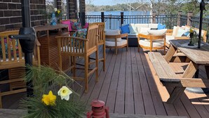 Une terrasse en bois avec des meubles d’extérieur, une lanterne et une vue sur un lac.