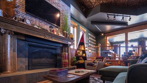 Un salon chaleureux avec une cheminée, des livres et un coin salon confortable.