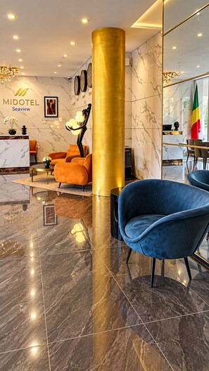 A modern hotel lobby with marble flooring, a reception desk, and a blue armchair. - Hotel Midotel Seaview (Pointe-Noire)