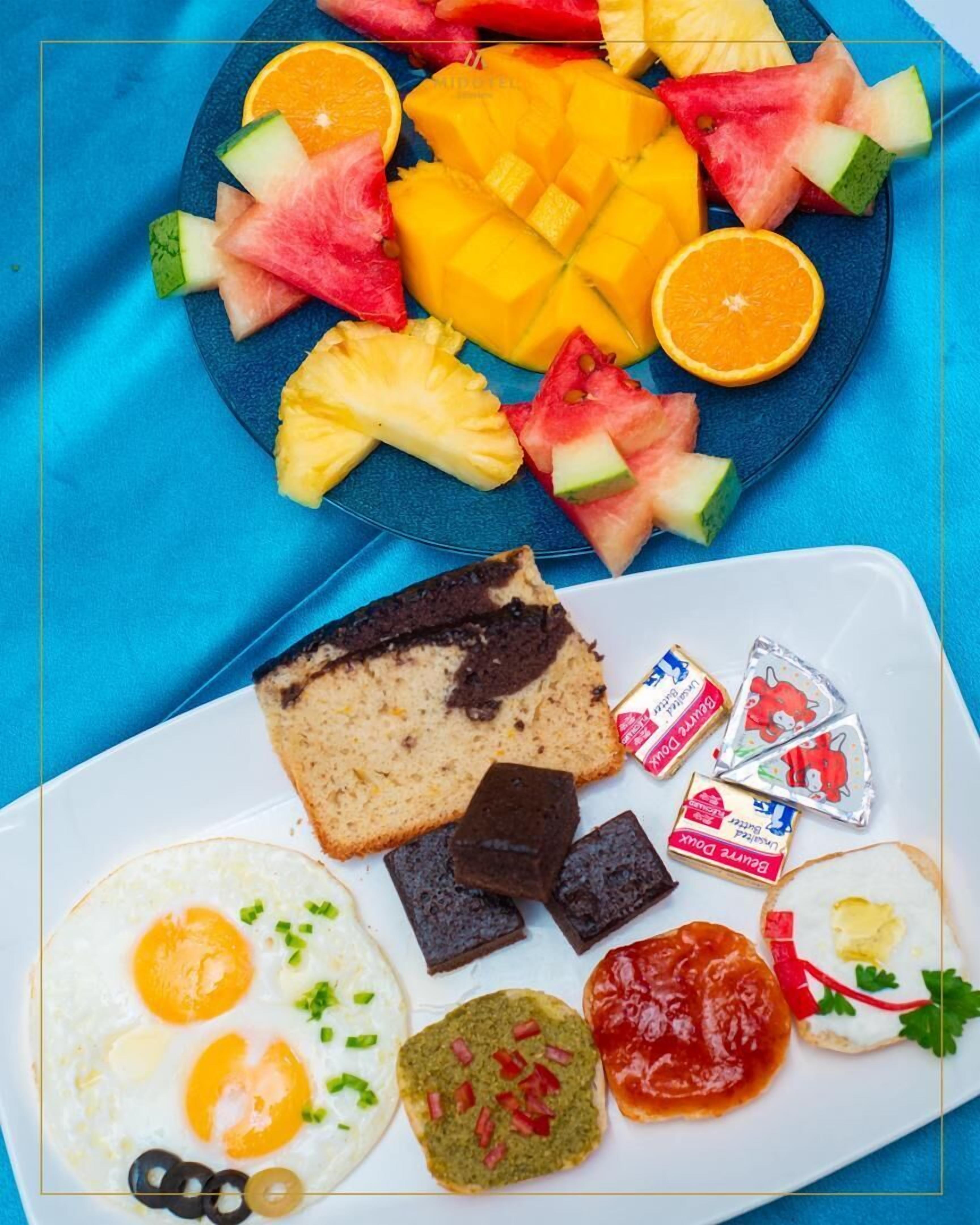 Un plato de desayuno con huevos, tostadas, chocolate y diversas frutas.