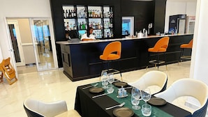 A restaurant with a bar area, tables set with plates, glasses, and cutlery, and a bar stocked with various bottles. - Hotel Midotel Seaview (Pointe-Noire)