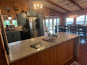 A kitchen with wooden walls, a granite countertop, stainless steel appliances, and a dining area with a table and chairs.