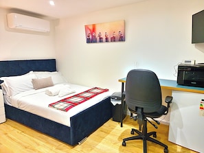 Una camera da letto con un letto, una scrivania, una sedia, un forno a microonde e un condizionatore d'aria a parete.