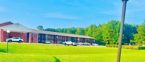 A motel with a brick facade, a covered parking area, and a well-maintained lawn.