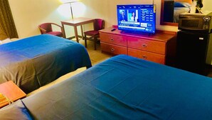 A hotel room with two beds, a desk, a chair, a television displaying a news channel, and a microwave. - The ashley inn (Crossett)