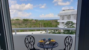 Ein Balkon mit zwei Stühlen und einem Tisch, mit Blick auf Gebäude und Grünflächen.