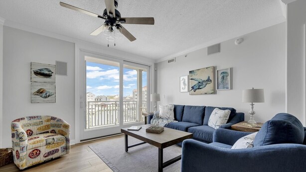 A living room with a blue sofa, a patterned armchair, a coffee table, and artwork on the walls. - Boardwalk to Beach ready! Boat Slip & Parking. (Ocean City)