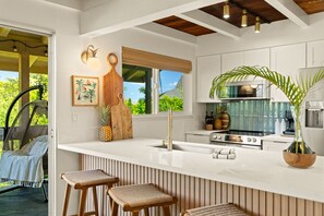A modern kitchen with a large island, white cabinetry, and a view of the outdoors.