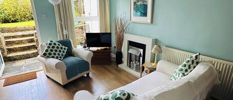 A bedroom with two beds, a TV, a fireplace, and a view of the garden.