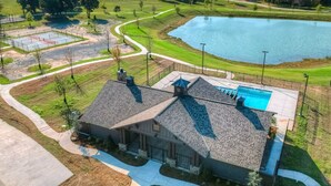 Una casa grande con piscina, cancha de tenis y estanque.