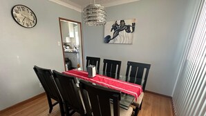 A dining area with a round table, black chairs, a red tablecloth, a chandelier, and a painting on the wall. - Winnipeg Spotless cozy 4-bedroom home (Winnipeg)