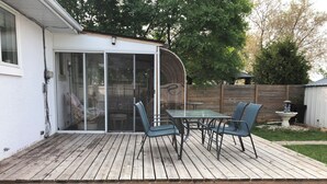 A wooden deck with a glass door leading to a covered patio area. - Winnipeg Spotless cozy 4-bedroom home (Winnipeg)