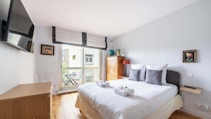 A bedroom with a bed, a desk, a wardrobe, and a window with a view.