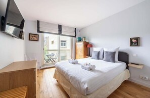 Een slaapkamer met een bed, een bureau, een kledingkast en een raam met uitzicht.