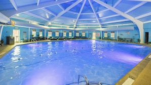An indoor swimming pool with a high ceiling and blue walls.