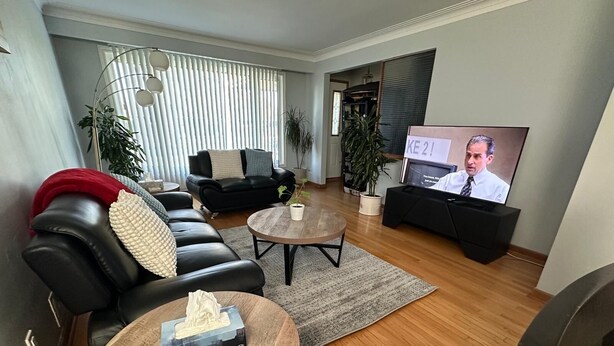 A living room with a black leather sofa, a wooden coffee table, and a television on a stand. - Winnipeg spotless Cozy 3 bedrooms home (Winnipeg)