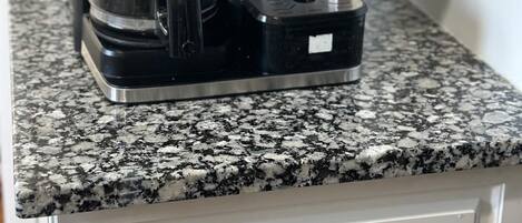 Una cafetera Hamilton Beach FlexBrew damunt un taulell de granat, a prop d'un calaix blanc.