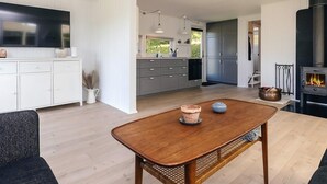 Una cocina moderna con gabinetes grises, una estufa negra y un comedor con mesa de madera.