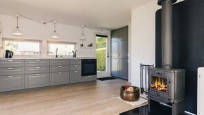 Una cocina moderna con gabinetes grises, una estufa negra y un amplio ventanal.