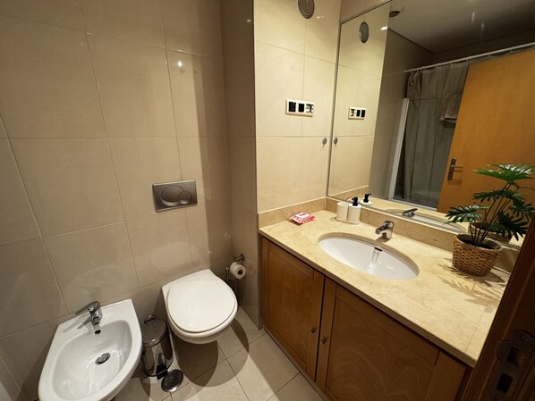 A modern bathroom with a sink, bidet, and toilet. - Riverside Expo (Lisbon)