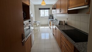 Eine Küche mit Holzschränken, einem Edelstahl-Kühlschrank, einem eingebauten Backofen, einer Spüle und einem Fenster.