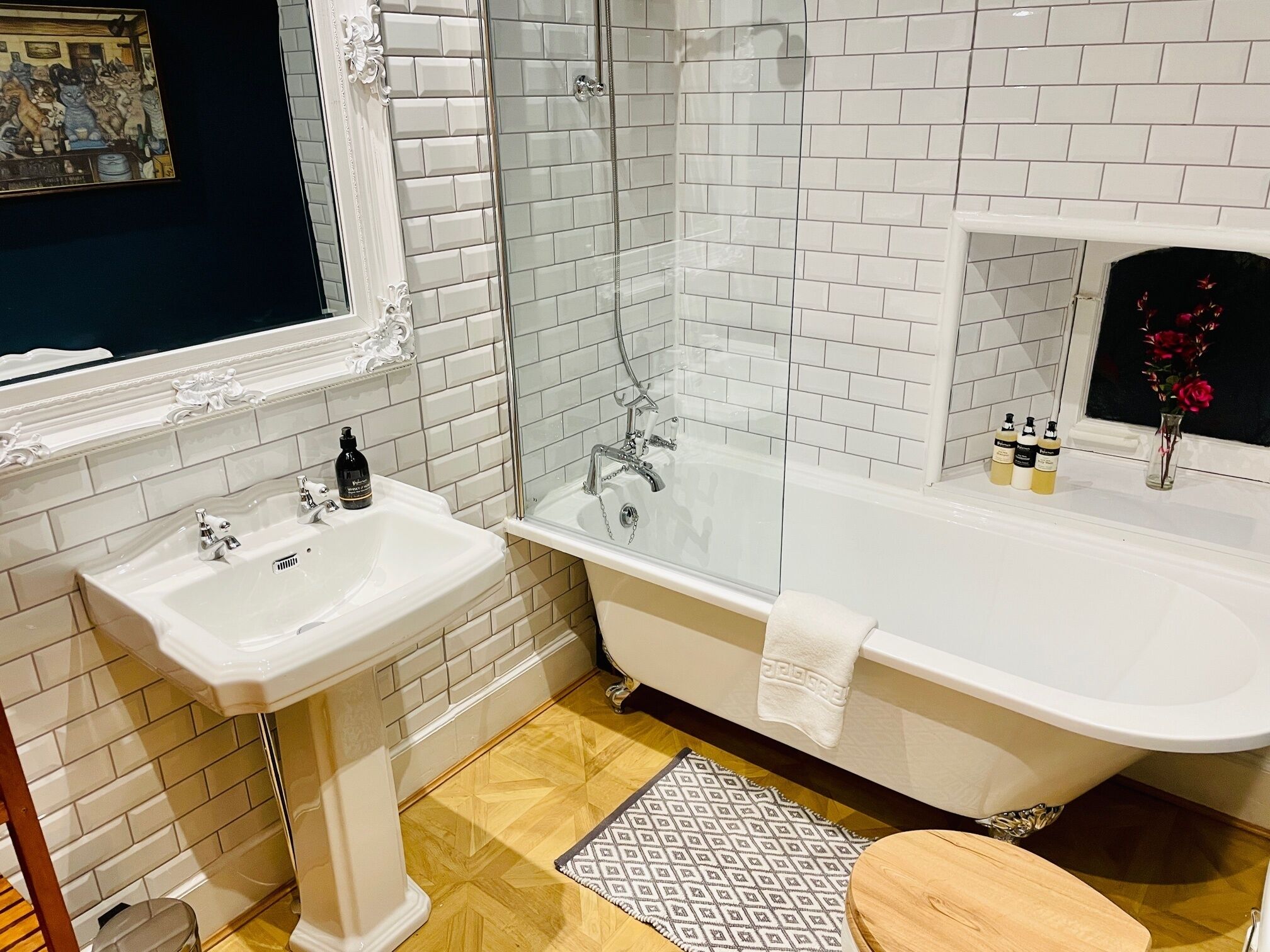 A bathroom with a white sink, a bathtub, and a shower. There are toiletries on the sink and a towel on the bathtub.