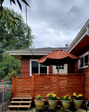 Une maison en bois avec un porche, un espace salon couvert et des plantes en pot.