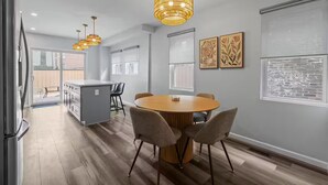 A modern kitchen with a central island, pendant lighting, and a dining area with a round table and chairs.