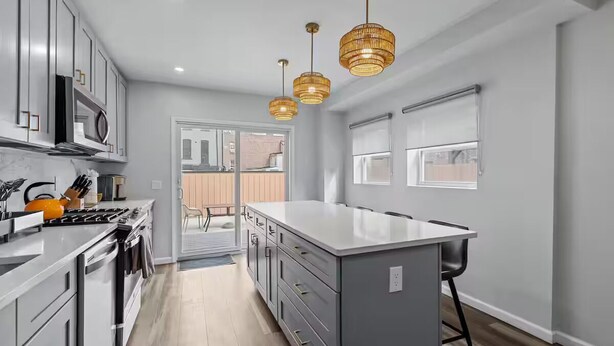 A modern kitchen with grey cabinets, a central island, and pendant lighting.