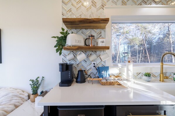 Una cocina moderna con encimera blanca, cafetera, tostadora y felpudo.