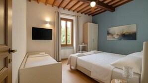 A bedroom with a bed, a wardrobe, a bedside table, a lamp, and a painting on the wall. - Villa La Gioconda - Con Piscina Esclusiva (Arezzo)