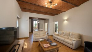 A spacious living room with a large flat-screen TV, two beige sofas, a wooden coffee table, and a brick ceiling. - Villa La Gioconda - Con Piscina Esclusiva (Arezzo)