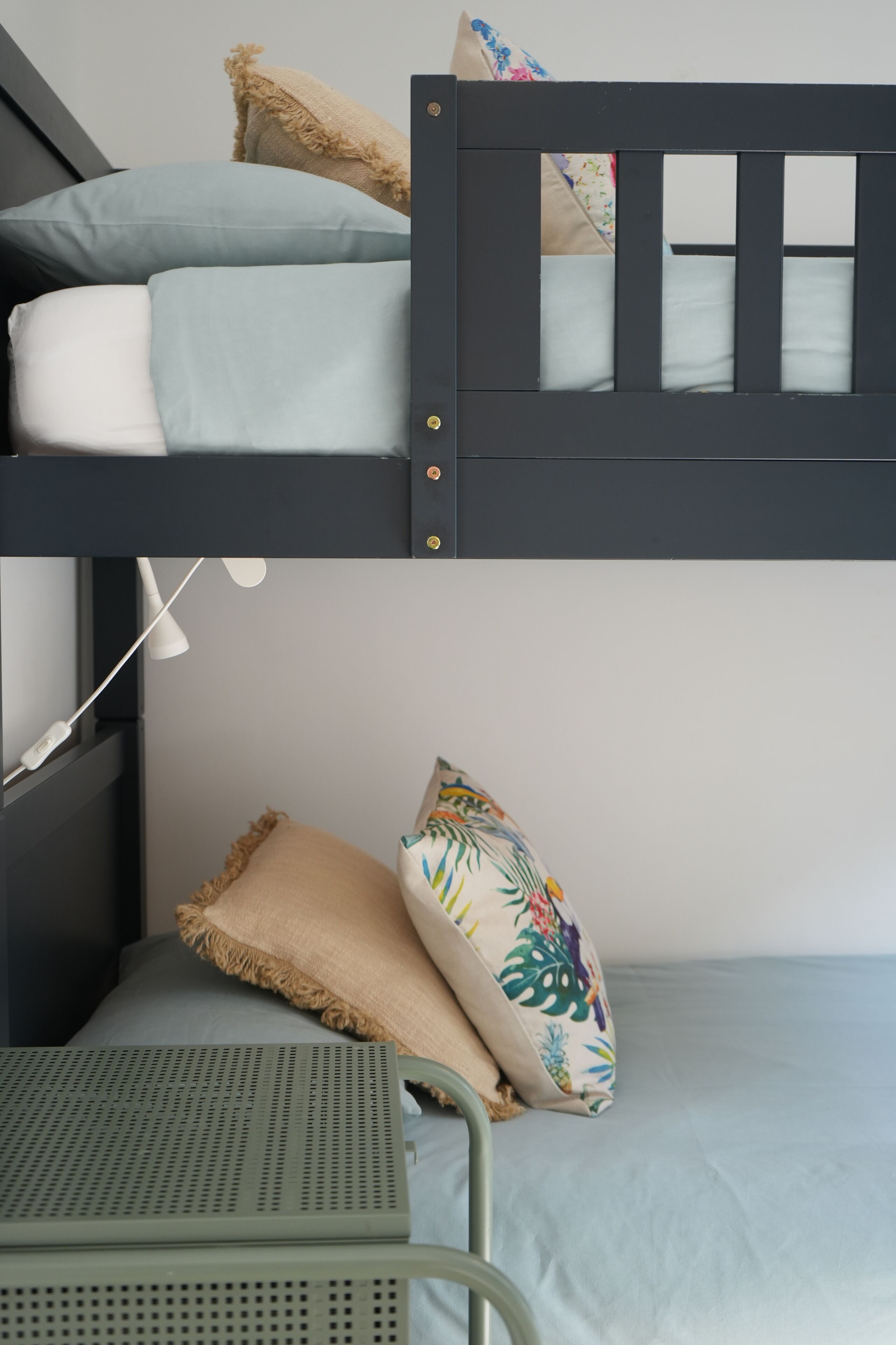 A bunk bed with a headboard, a pillow, and a metal chair.